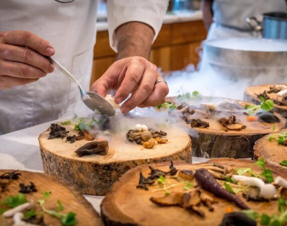 A picture of a chef placing items on a wood cutting block.