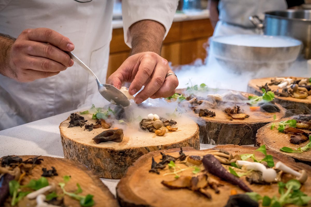 A picture of a chef placing items on a wood cutting block.