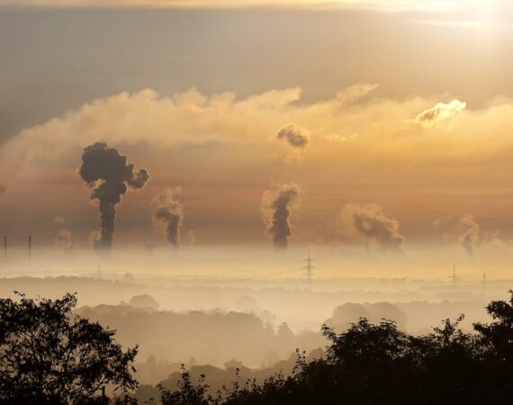 A picture of smog over a valley with plumes of smoke coming up from different buildings