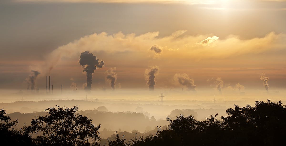 A picture of smog over a valley with plumes of smoke coming up from different buildings