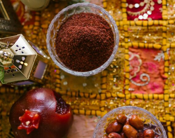 I picture of some food on a table cloth, including a pomegranate, dates, and a brown powder