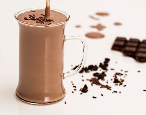 A picture of a chocolate smoothie in a glass mug with shavings of chocolate around it.